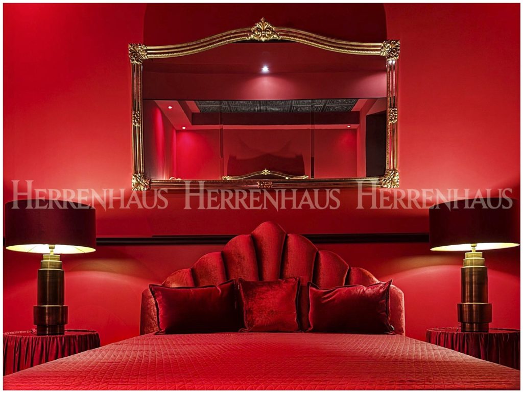 Verführerisches rotes Zimmer mit eleganter Einrichtung und opulentem Spiegel – stilvoller Rückzugsort im Premium Bordell Berlin.
