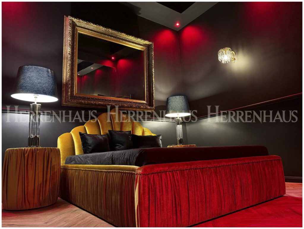 Exklusives Schlafzimmer mit Designerbett, roter Ambientebeleuchtung und Barockspiegel – stilvolles Interieur im gehobenen Bordell Berlin.