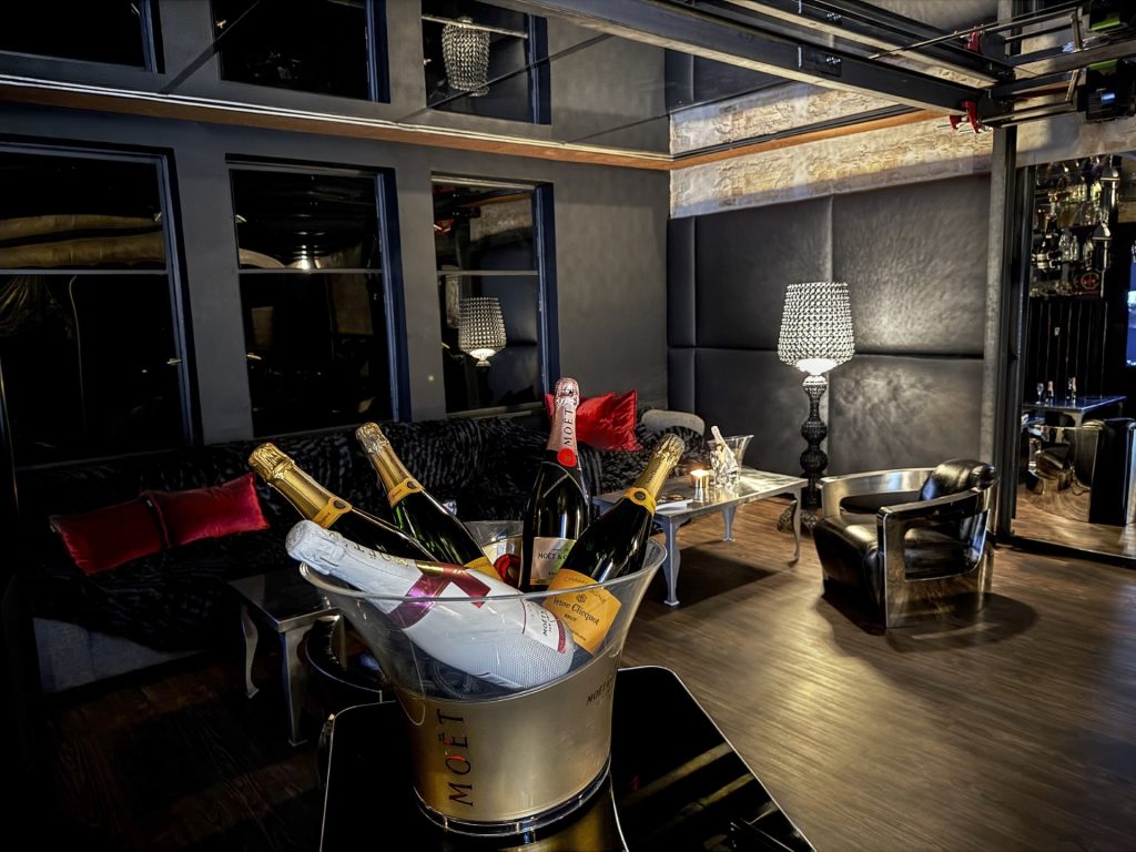 Sektkühler mit edlen Champagnermarken auf einem Tisch in der stilvollen Lounge des Berliner Bordell Herrenhaus